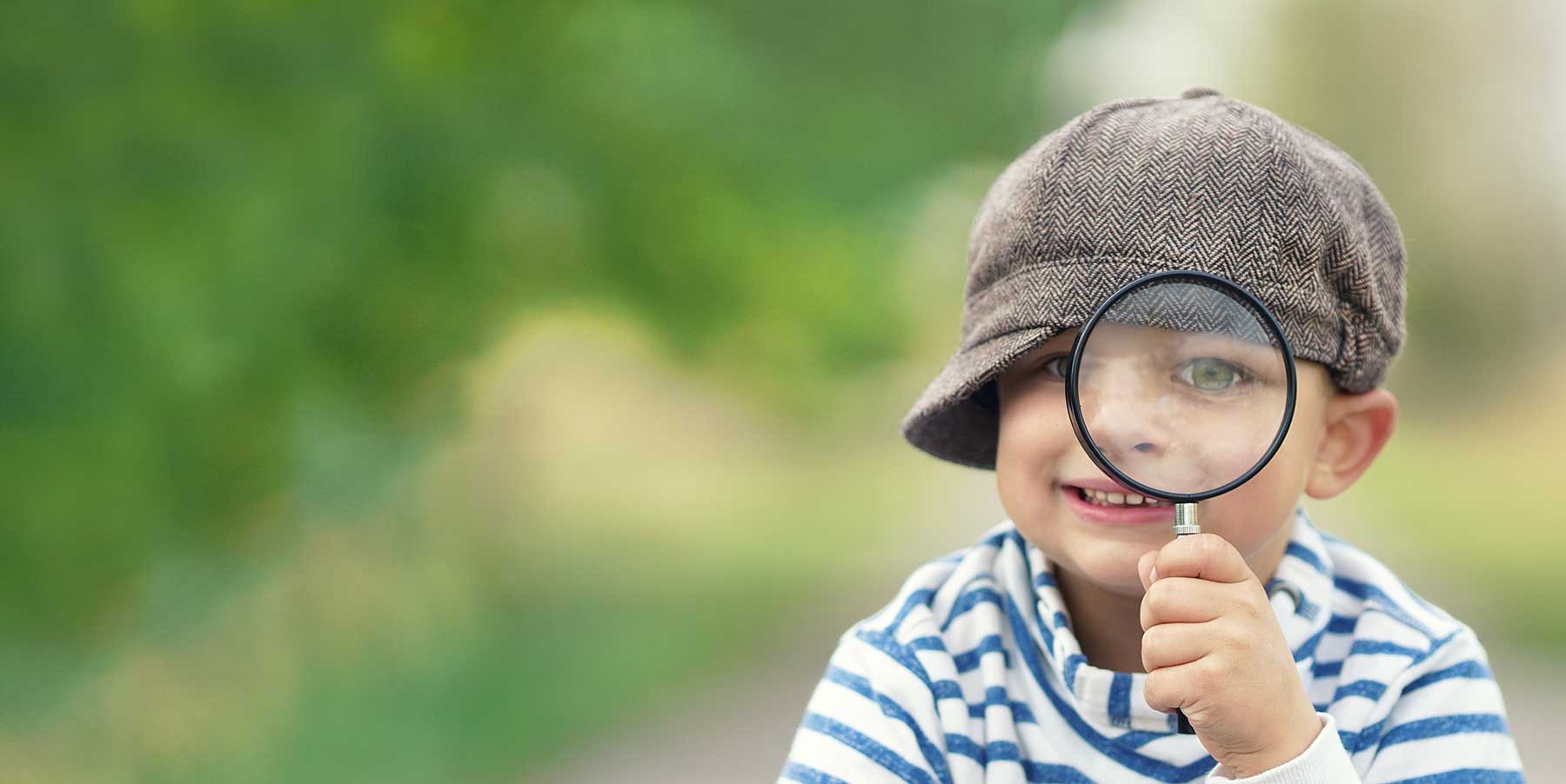 little boy wearing newsboy cap holding magnifying glass